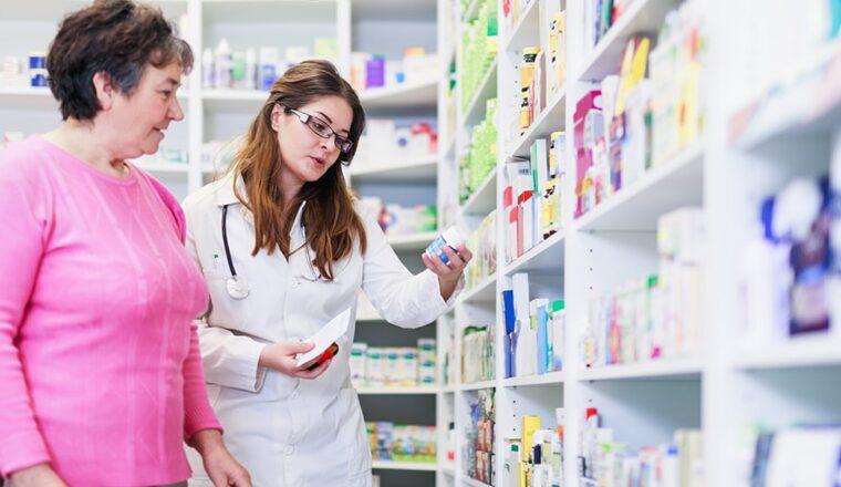 Pharmacist reading the label of a bottom to a customer.