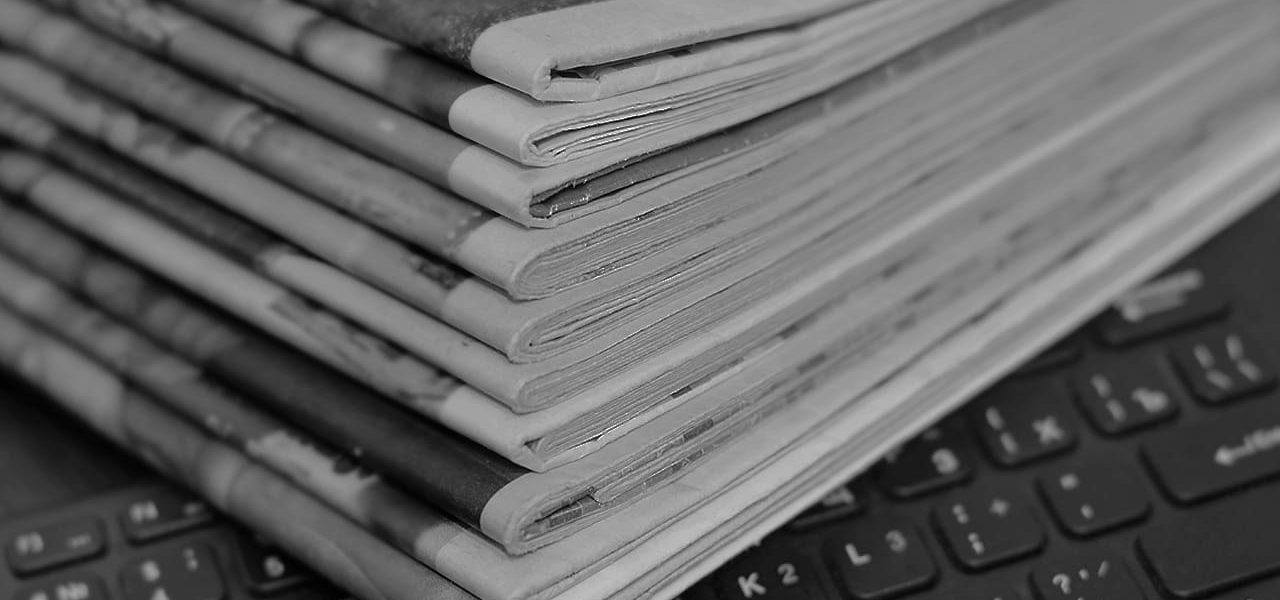 Stack of newspapers on a computer keyboard.