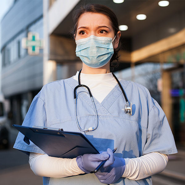 Nurse holding clipboard standing outside of hospital