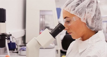 Researcher in lab looking through microscope