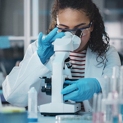 Researcher looking through a microscope in a preclinical study basic research lab.