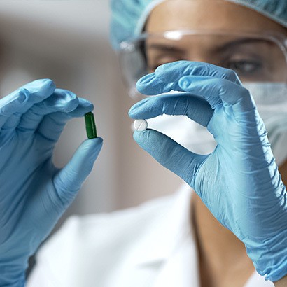 Researcher holding a gel pill and solid pill during a preclinical phase three lead optimization and dosage formulation