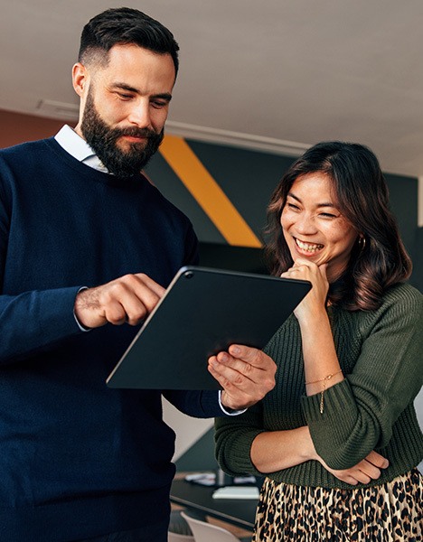 Two field experts speaking while examining a report on a tablet.